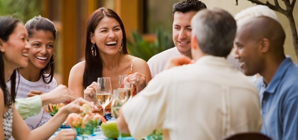 A group of friends smiling and enjoying a meal and drinks in Austin, Texas.