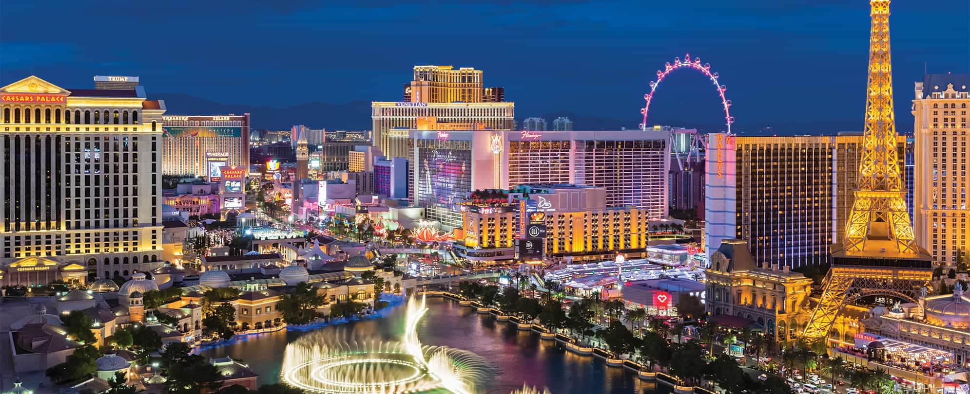 The Bellagio Fountain, Eiffel Tower, and Las Vegas skyline lit up at night.