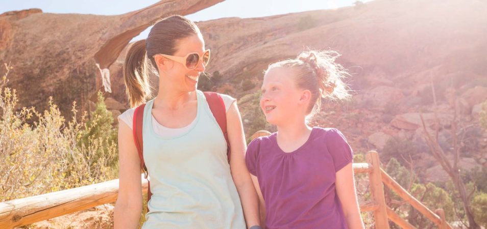 A mother and daughter, standing at an observation deck overlooking Red Rocks in Moab, Utah. 