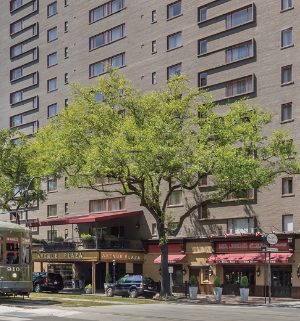 The exterior of the Avenue Plaza timeshare resort in New Orleans, Louisiana with a trolly car in front. 