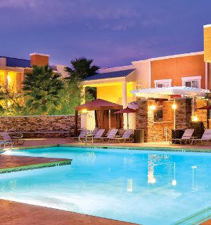 The outdoor pool of WorldMark Tropicana surrounded by sun loungers and cabanas.