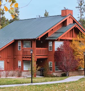 The exterior of WorldMark Big Bear, a cabin-style timeshare resort, surrounded by trees with autumn leaves.