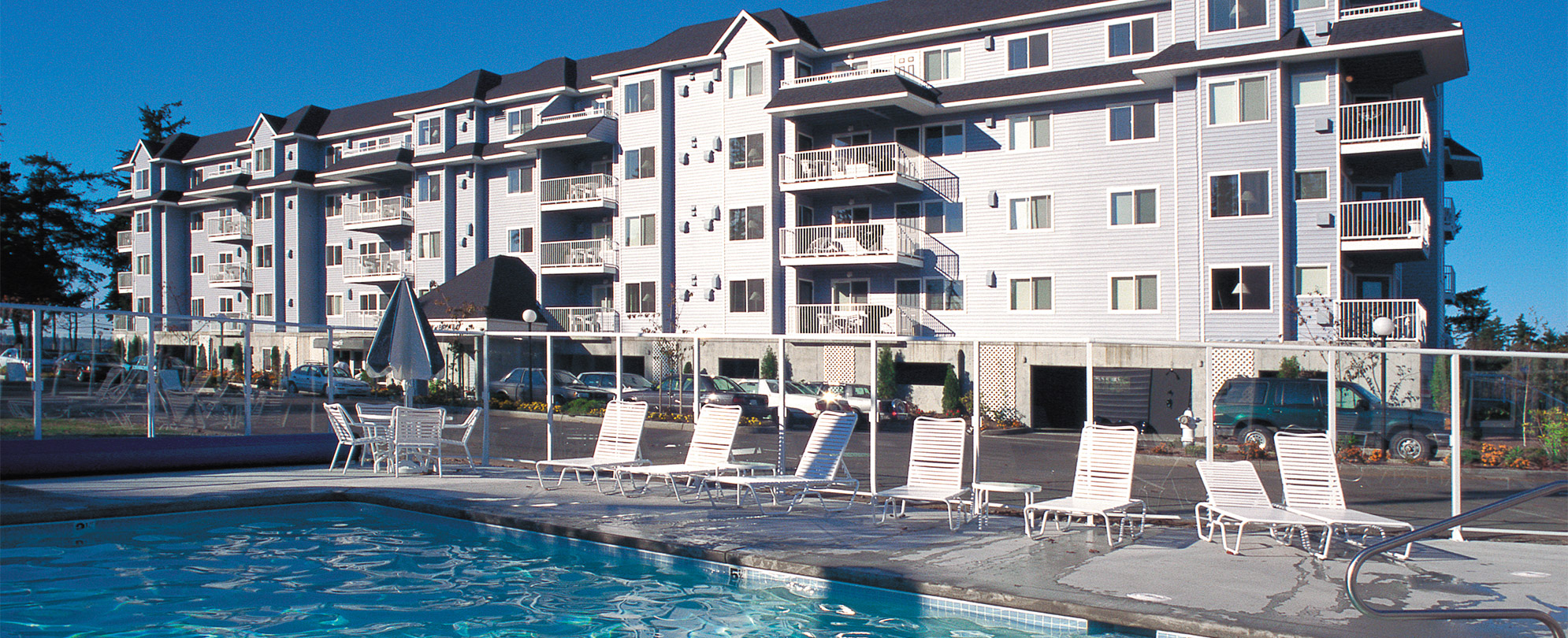 A pool surrounded by lounge chairs in front of the Wyndham Birch Bay Resort.