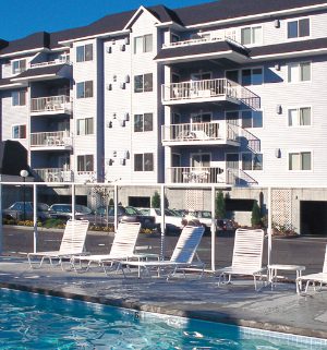 A pool surrounded by lounge chairs in front of the Wyndham Birch Bay Resort.