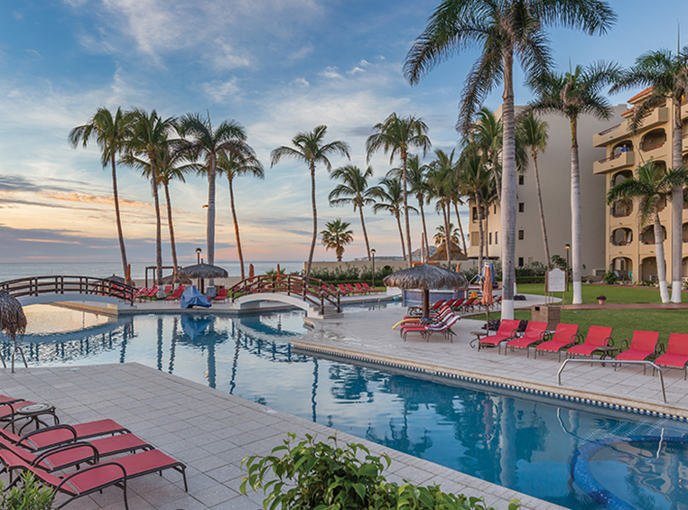 The oceanfront pool surrounded by lounge chairs and palm trees at WorldMark Coral Baja in San José del Cabo, Mexico.