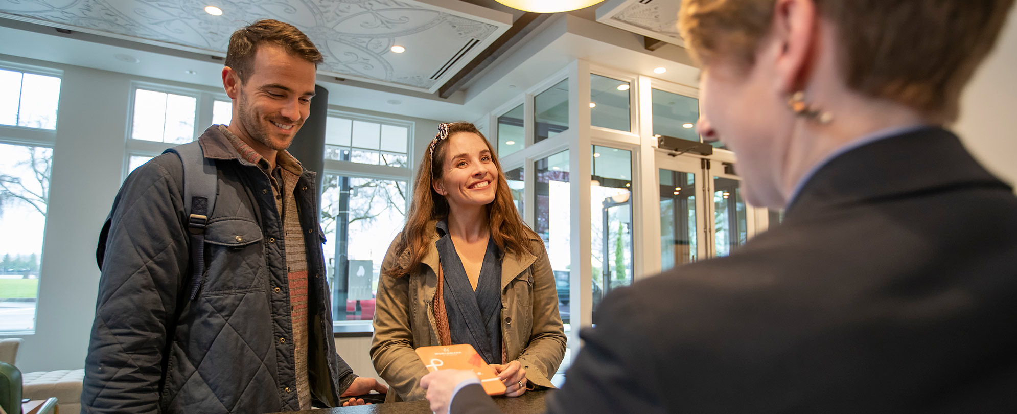 A couple checking in and being handed their room keys at the front desk of a WorldMark by Wyndham resort. 