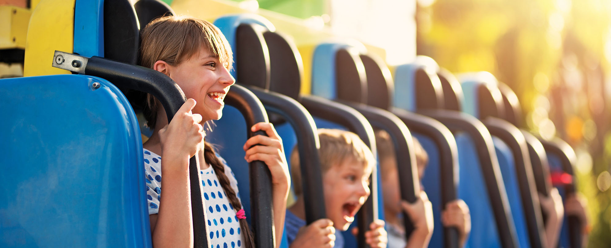 Smiling kids hold onto safety bars on a theme park ride.