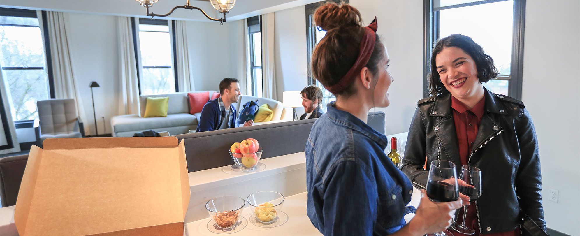 Two smiling women stand in a WorldMark resort kitchen talking and drinking wine.