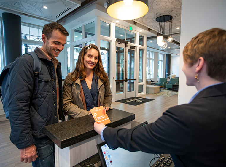 A man and woman smile at a WorldMark employee standing at the resort front desk.