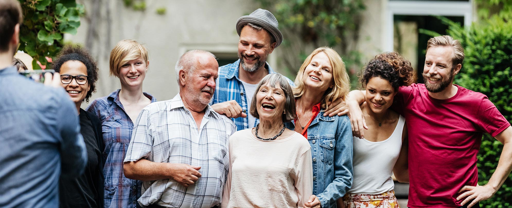 Eight adult members of a family stand smiling posing for a picture.