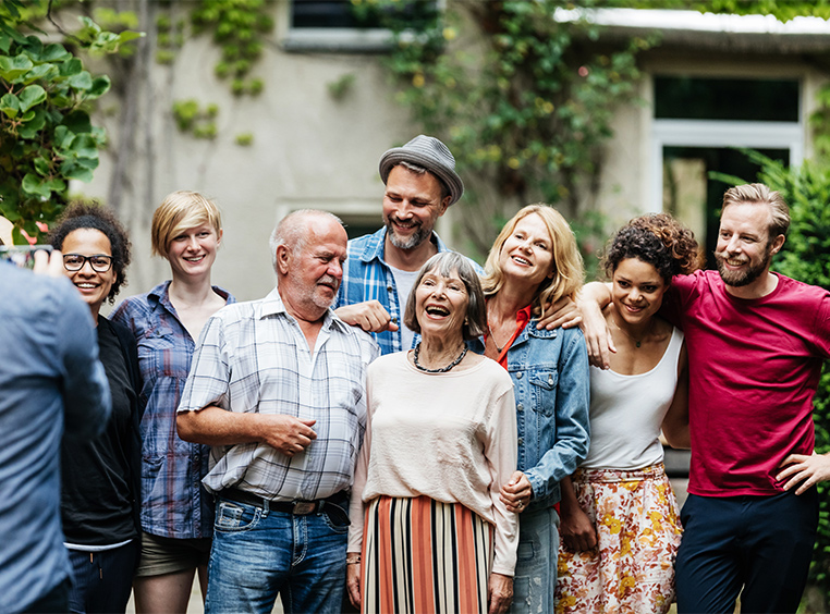 Eight adult members of a family stand smiling posing for a picture.