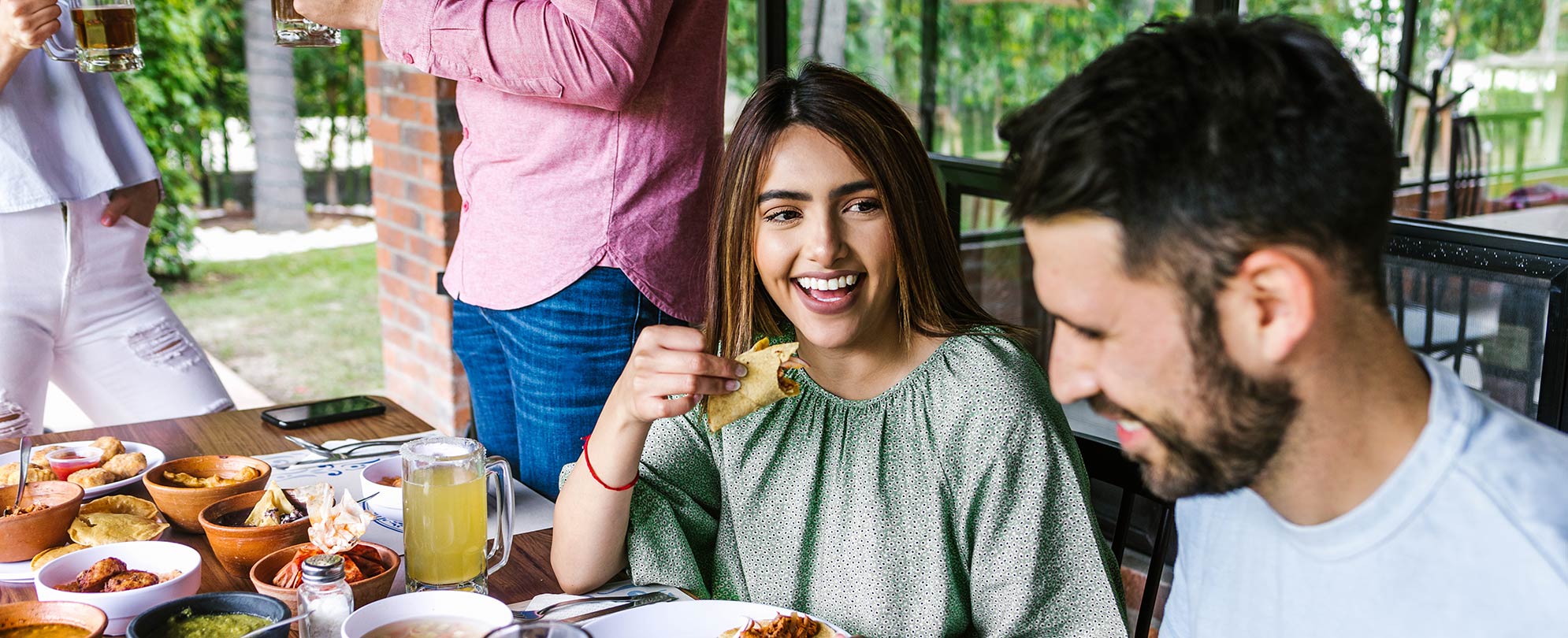 A woman smiling and eating a taco